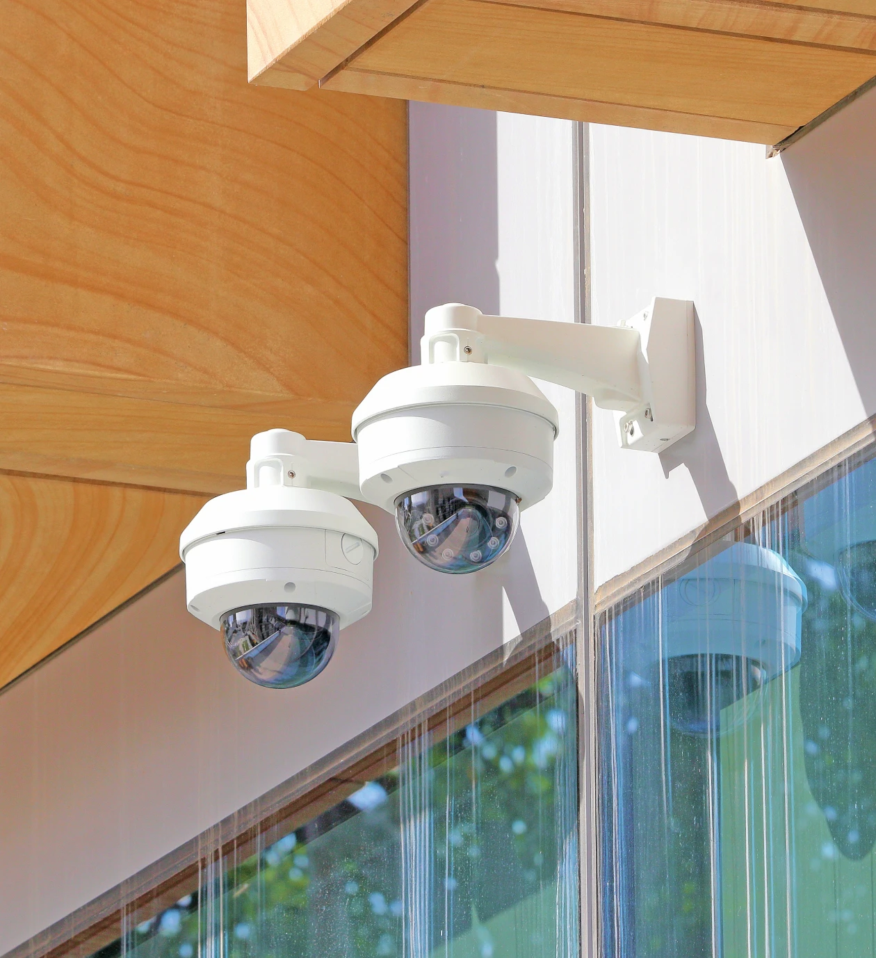 Twin security cameras on glass building exterior